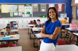 Teacher wearing blue shirt in front of classroom