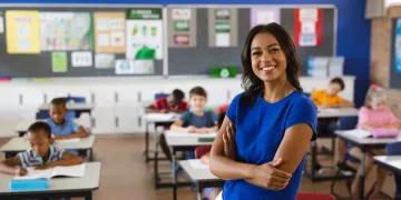 Teacher wearing blue shirt in front of classroom