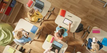 Overhead view of students on computers and tablets in a classroom