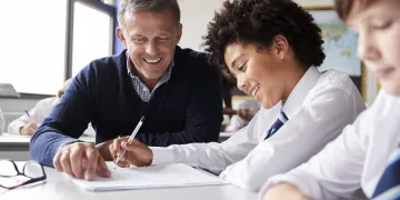 High School Tutor Giving Male Student Wearing Uniform One To One Tuition At Desk 