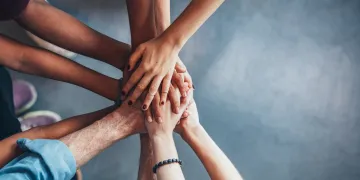 Close up top view of people putting their hands together