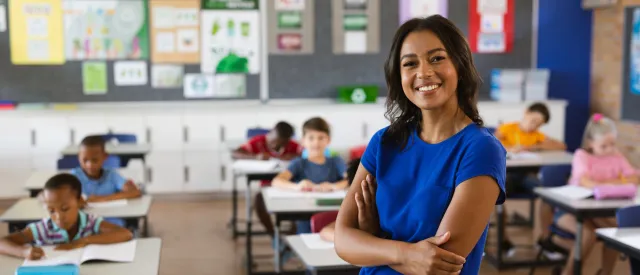 Teacher wearing blue shirt in front of classroom