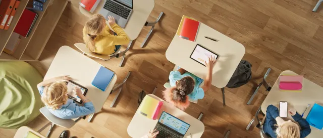 Overhead view of students on computers and tablets in a classroom