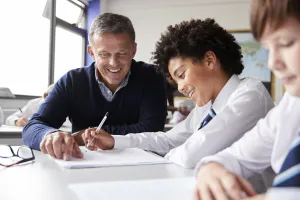 High School Tutor Giving Male Student Wearing Uniform One To One Tuition At Desk 