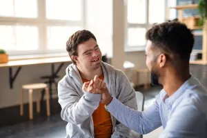 man with down syndrome and tutor grabbing hands